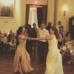 Sira, a belly dancer, encourages a bride to join her on the dancefloor surign the wedding reception